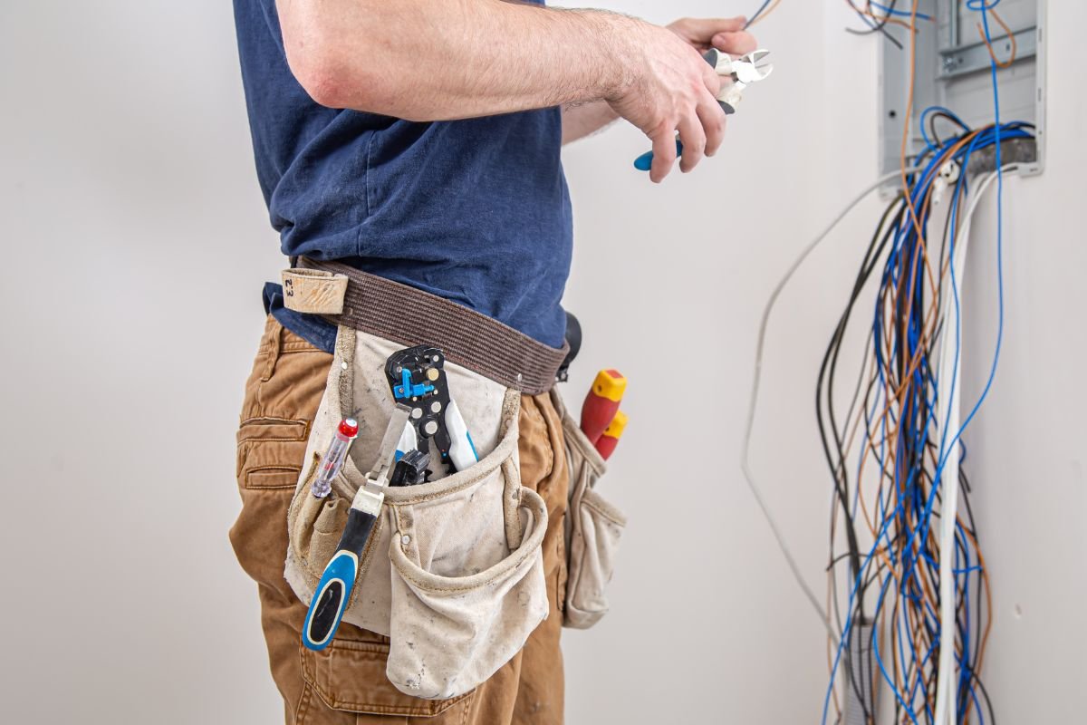 Electricista con alicates arreglando cuadro de luz